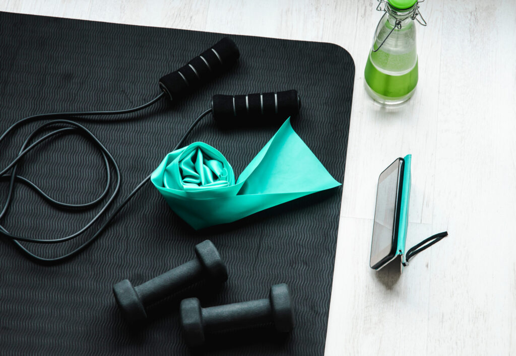 家庭用トレーニング器具、縄跳び、抵抗運動用のラテックスゴムバンド、ダンベルを上から見た図。オンライントレーニングクラスのコンセプト。スマートフォン画面からの動画